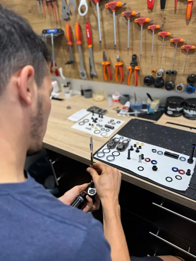 Mantenimiento de un amortiguador en la mesa del taller, con el panel de herramientas detrás