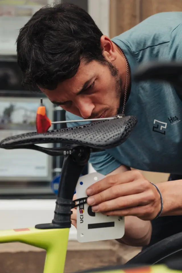 Kike ajustando el sillín y el dorsal de una bici de carretera en una carrera UCI