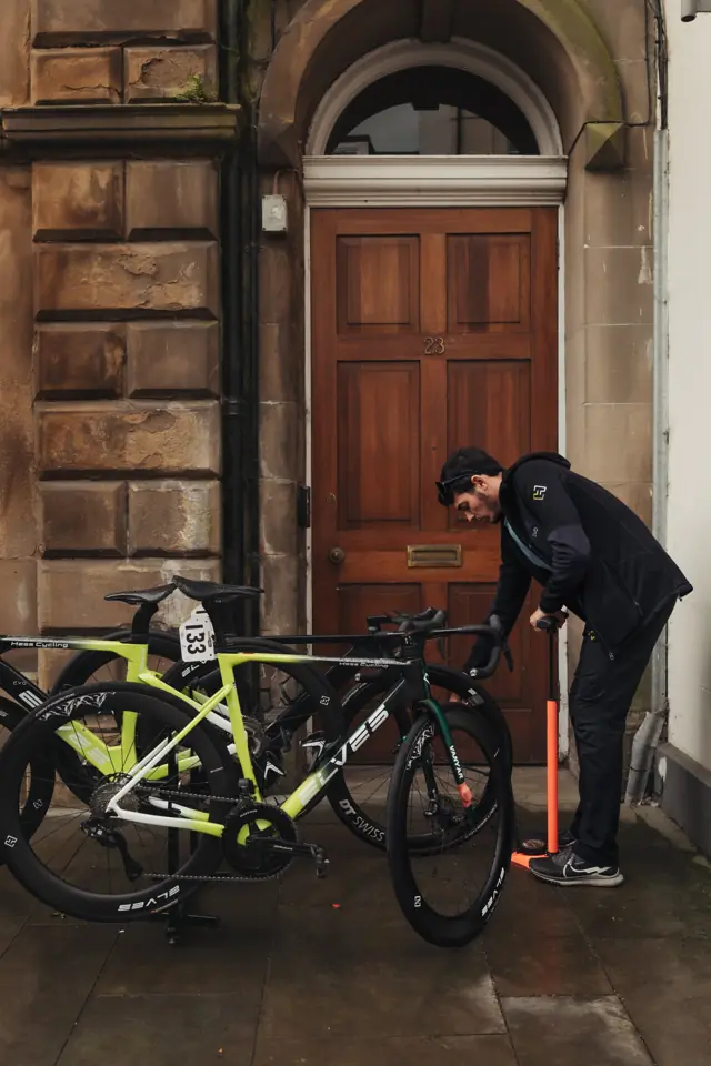 Kike inflando las ruedas de las bicis del equipo en la calle antes de una carrera